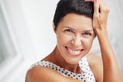 woman loving the look of her smile after getting dental bridges at Comprehensive Dentistry