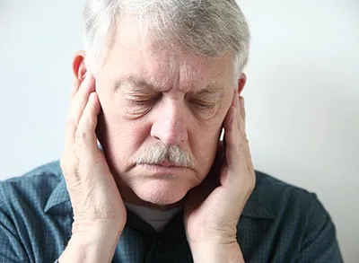 man holding his jaw experiencing TMJ pain