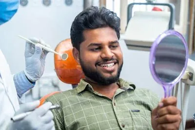 man looking in the mirror at his freshly cleaned smile